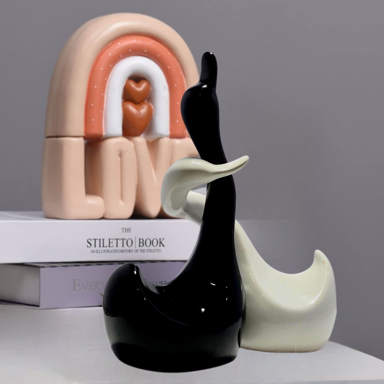 Close-up of the intertwined necks of the black and white ceramic duck statues on a kitchen countertop.
