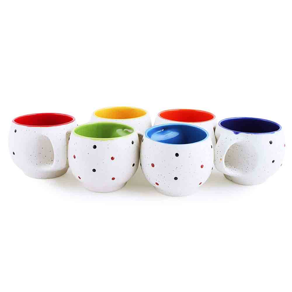 White ceramic tea cup with black dots and colorful interior on a kitchen counter.