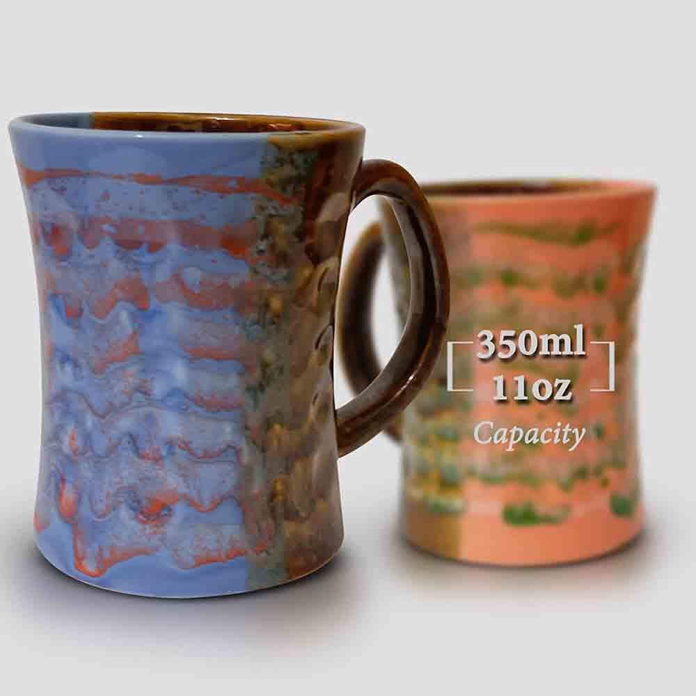 Blue and orange ceramic coffee mug with artistic brush strokes on a kitchen counter.