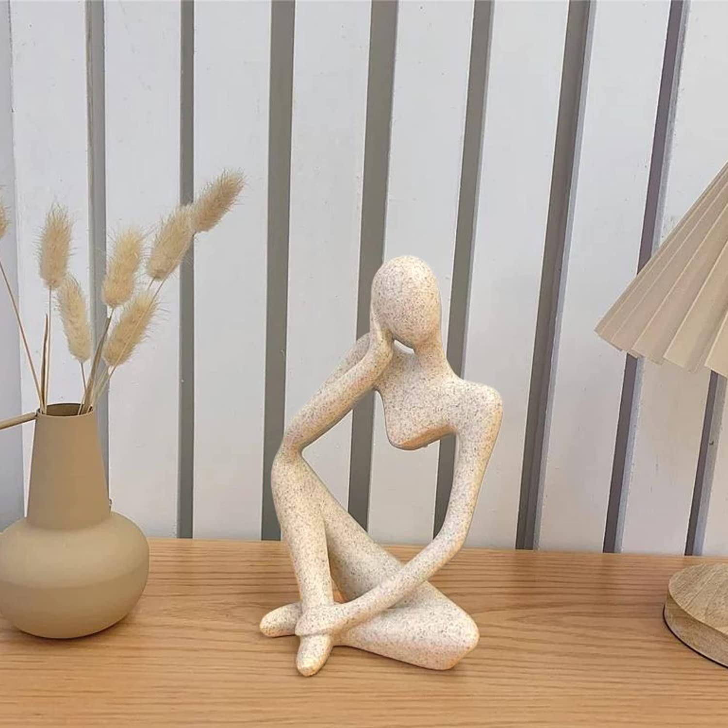 Thinking Men Statue trio in beige positioned against kitchen backsplash.