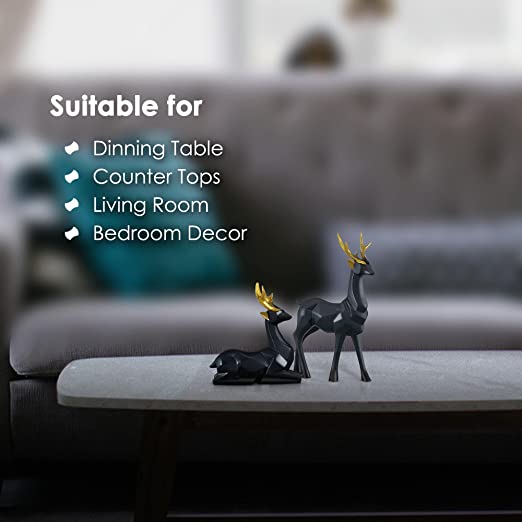 Alt Text: "Close-up view of golden and black Deer Family Statue with geometric cuts, featuring the sitting deer next to a potted plant on a kitchen counter."